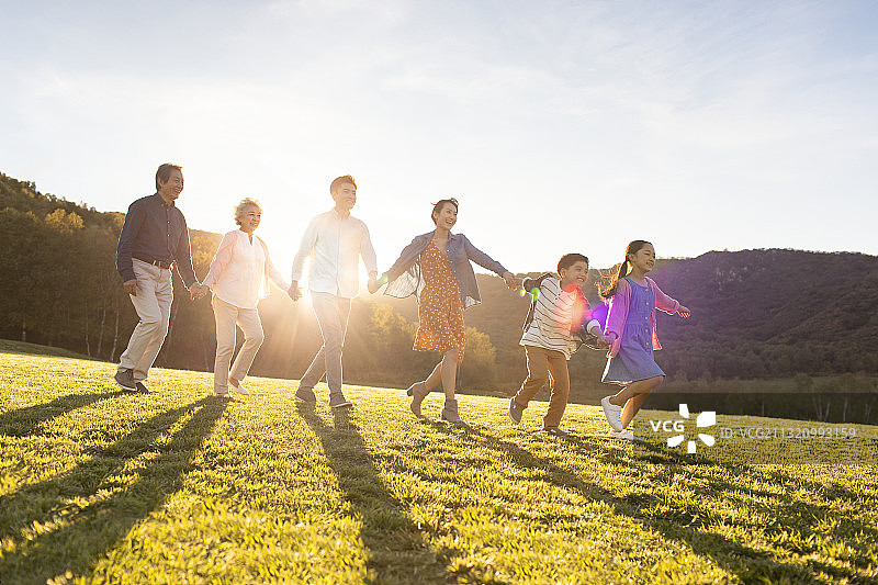 快乐的家庭手牵手在草地上散步图片素材