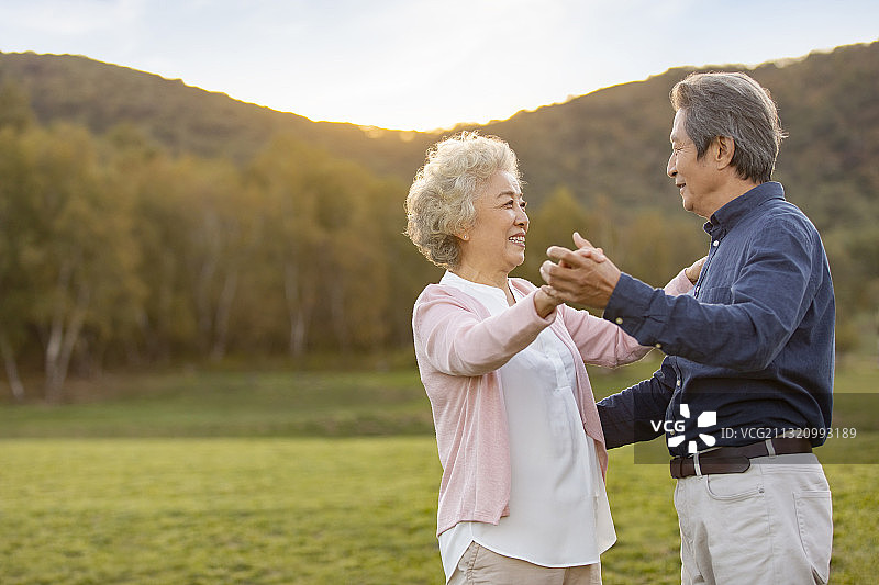 快乐的老年夫妇在草地上跳舞图片素材