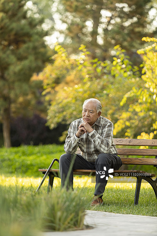 孤独的老人坐在公园长椅上图片素材