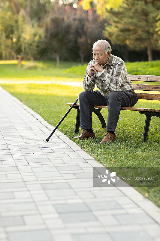 孤独的老人坐在公园长椅上图片素材