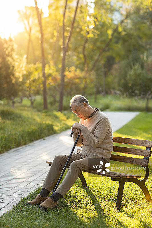孤独的老人坐在公园长椅上图片素材