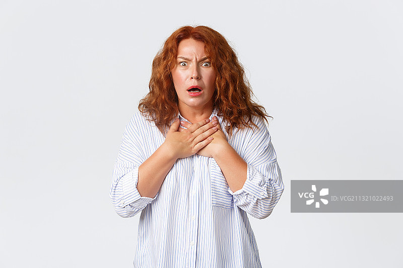 震惊的年轻女子站在白色背景前的肖像图片素材