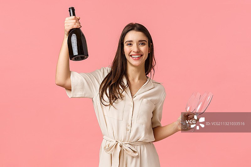 粉色背景下手持瓶子的微笑年轻女人肖像图片素材