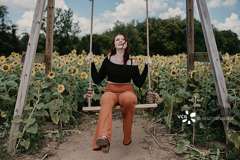 在美国印第安纳州南本德向日葵花田中荡秋千的年轻女人图片素材