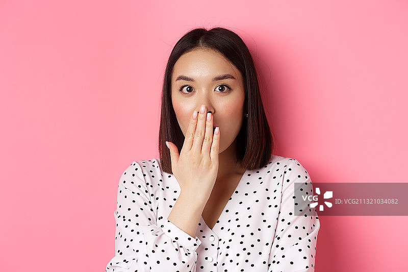 粉色背景下的震惊年轻女人图片素材