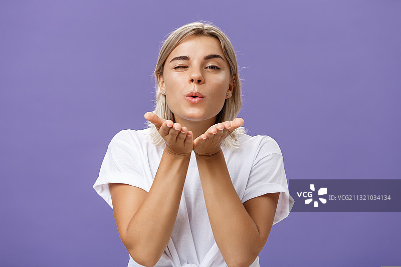 对着紫色背景飞吻的年轻女子肖像图片素材