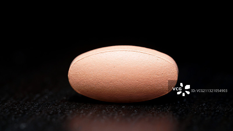黑色背景上的椭圆形药片图片素材