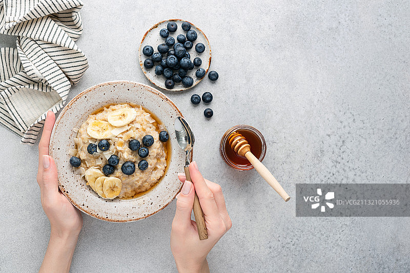女性手中的蓝莓蜂蜜燕麦粥（俄罗斯）图片素材