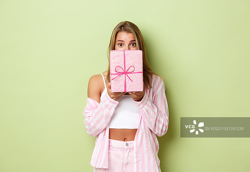 站在粉色背景前手持礼品盒的女孩肖像照图片素材