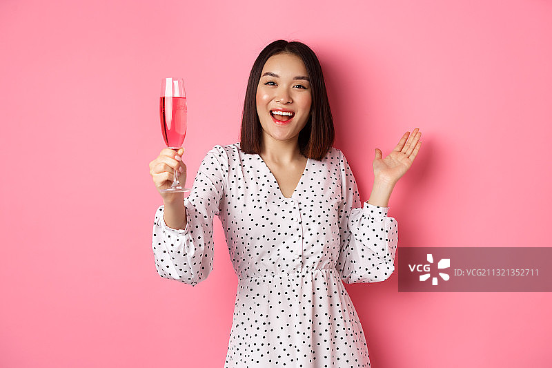 微笑女人站在粉色背景下手持饮料的画像图片素材