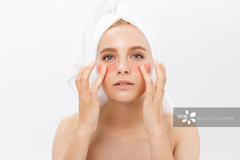 年轻女子在白色背景下涂抹面霜图片素材