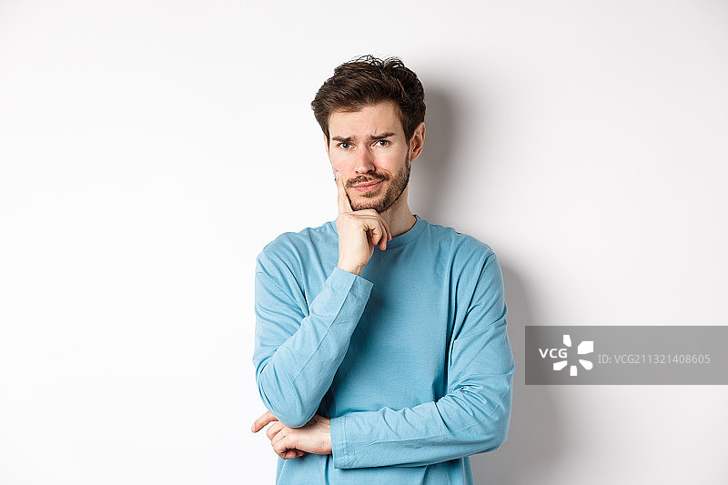 双手托腮靠在白色背景上的年轻男子图片素材