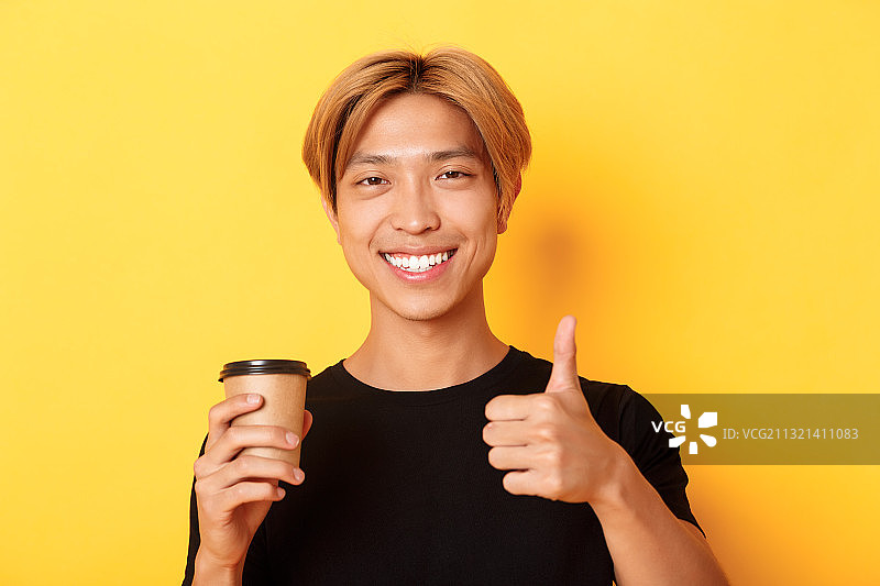 站在黄色背景下手势的微笑年轻女性肖像图片素材