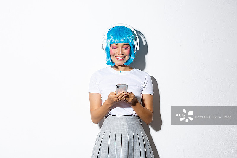 微笑的年轻女子听音乐使用手机白色背景图片素材