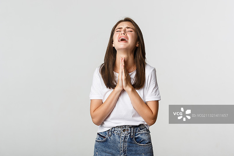 闭着眼睛站在白色背景前的微笑年轻女人肖像图片素材