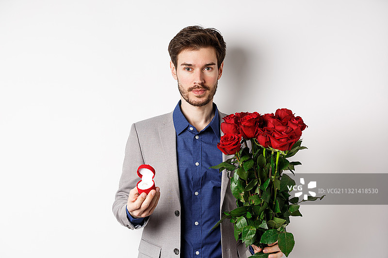 在白色背景下手持红玫瑰的年轻男子肖像图片素材