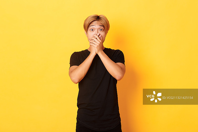 站在黄色背景前的年轻男人图片素材