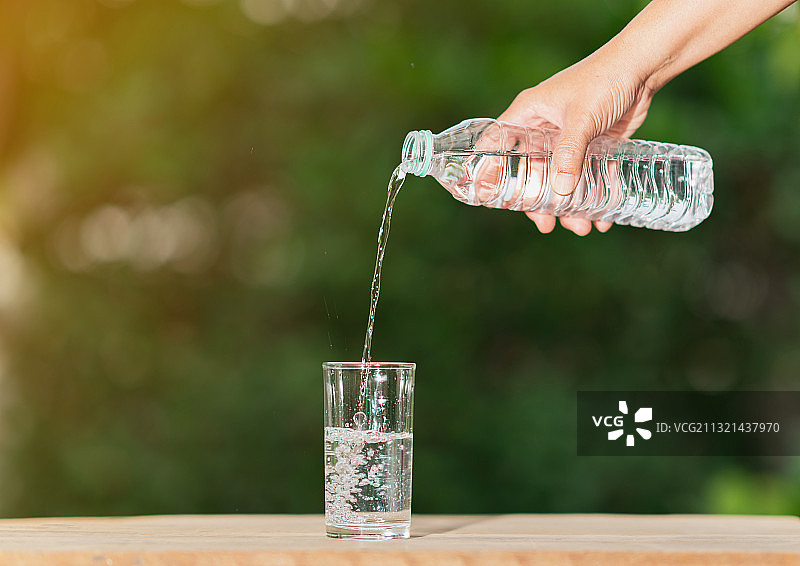 裁剪过的手在桌子上将水倒入瓶中图片素材