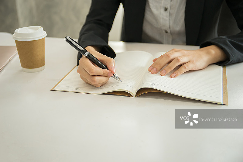在办公桌前写书的商务女性中部特写图片素材