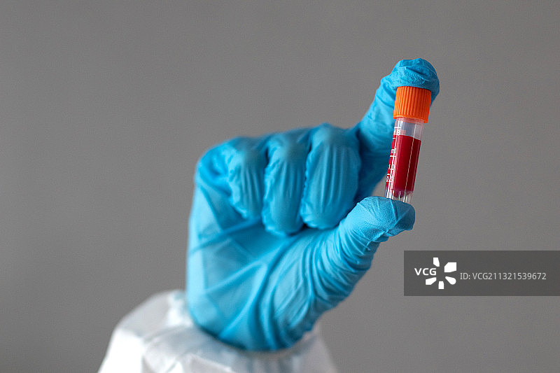 科学家在灰色背景下手持注射器特写图片素材