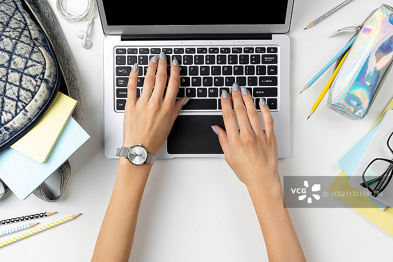 女子在桌旁使用笔记本电脑图片素材