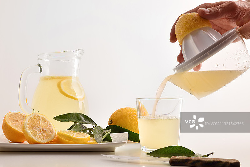 裁剪的手将橙汁倒入玻璃杯，白色背景图片素材