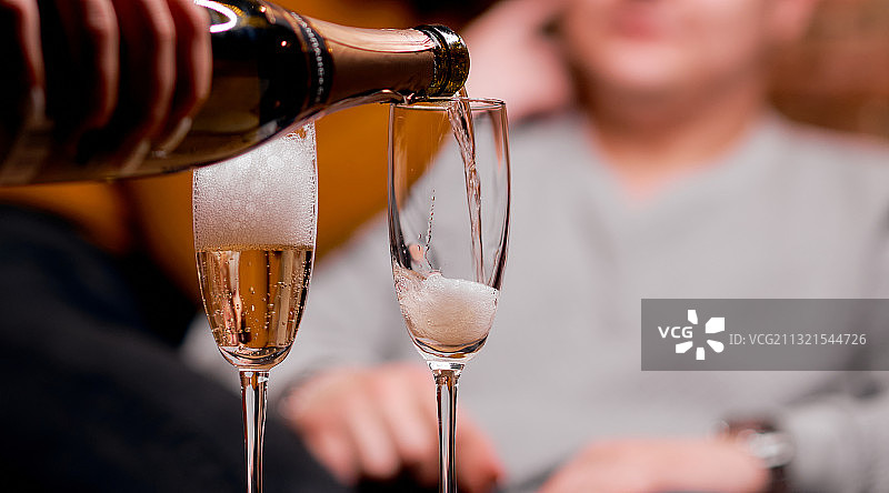 男子往玻璃杯中倒香槟的腰部特写图片素材