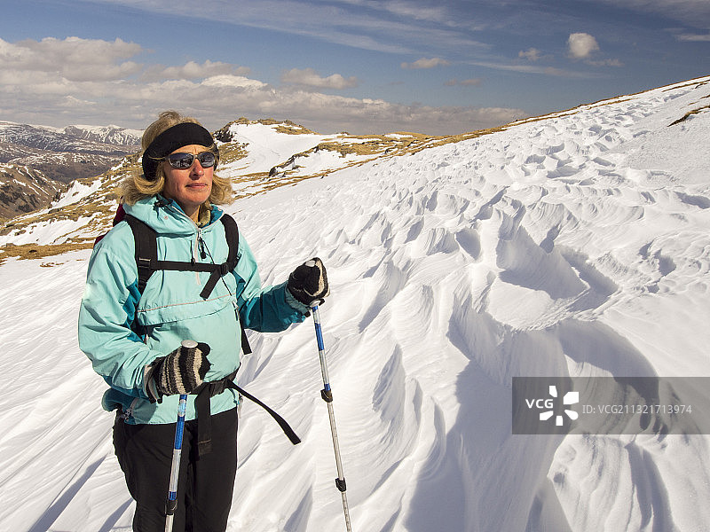 英国坎布里亚郡湖区，怀恩诺斯山口的强风雪景，一位徒步女性图片素材