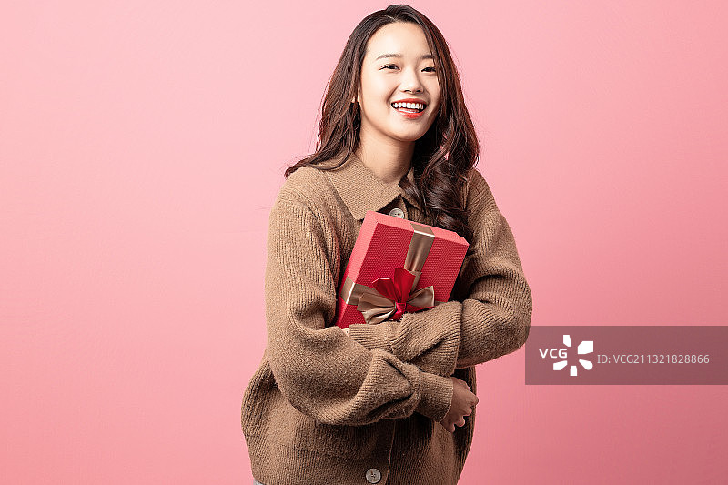 粉色背景里拿着礼物的美女图片素材