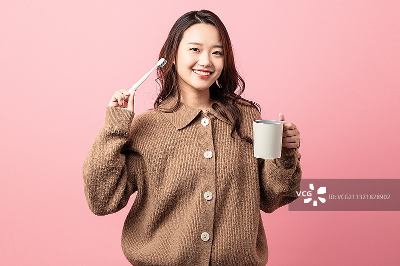 粉色背景里正在刷牙的美女图片素材