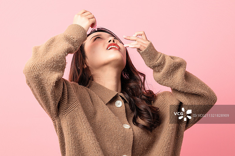 粉色背景里正在使用眼药水的美女图片素材