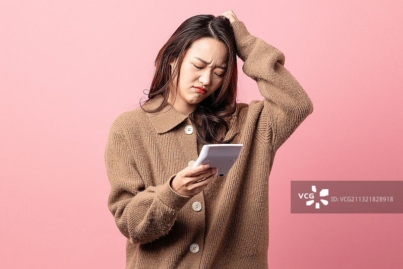 粉色背景里正在使用计算器的美女图片素材