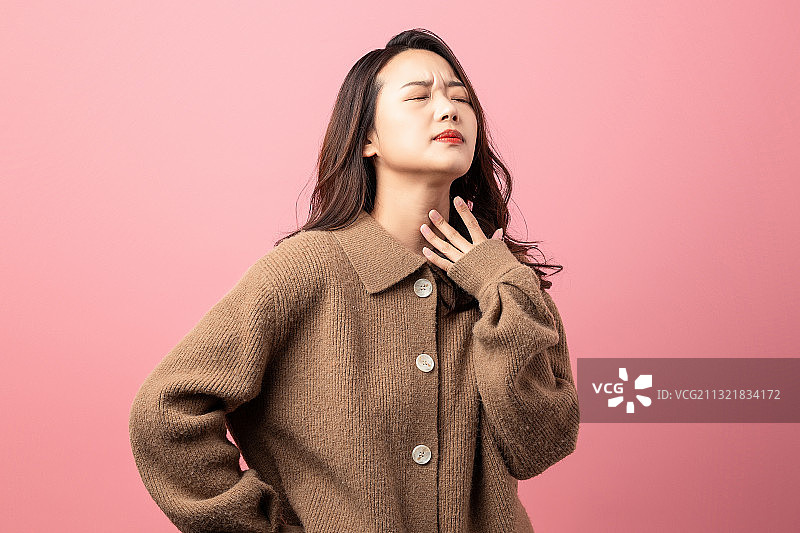 粉色背景里咽喉疼痛的东方美女图片素材
