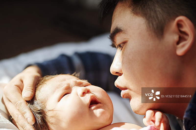 父亲亲吻哭泣的新生儿图片素材