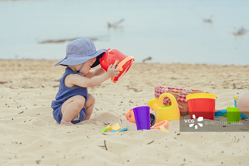 海滩上的快乐男婴与他的挖沙玩具图片素材