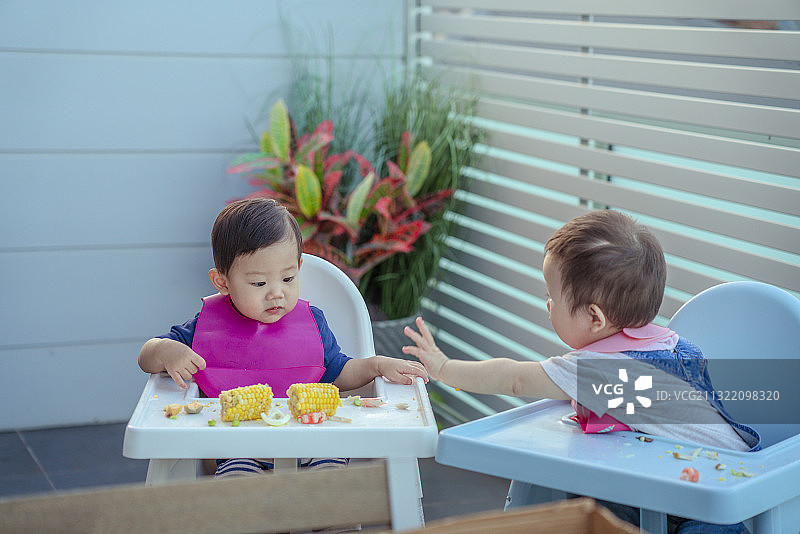 两个健康宝宝在婴儿餐桌上分享食物图片素材