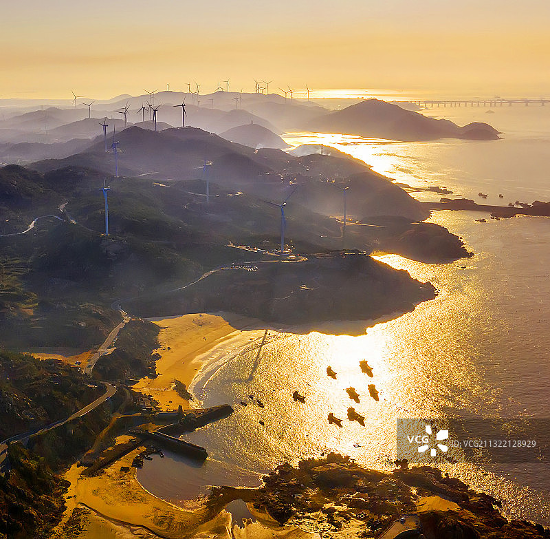 拍于福建平潭夕阳西下金色的余晖照耀着海面。港湾停靠着渔船图片素材