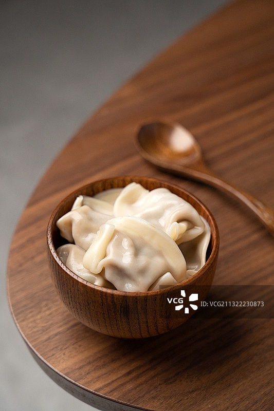传统美食古典厚重风格木制桌上的一碗饺子图片素材