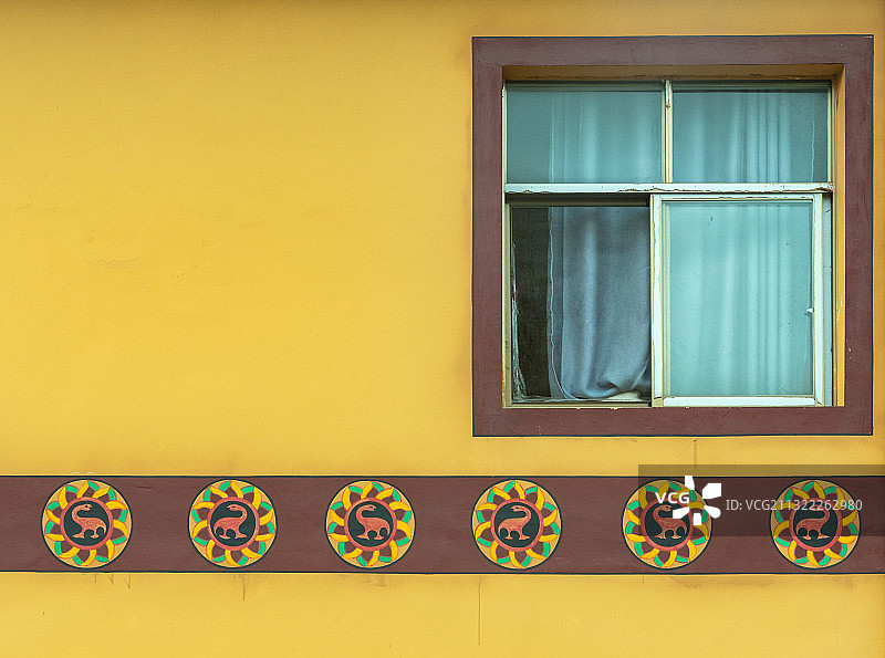 云南禄丰世界恐龙谷附近充满民族特色的民居，黄墙有恐龙标志图片素材