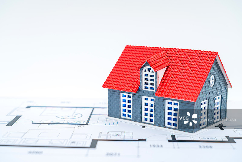 房子模型放在房屋户型图图纸上——买房装修概念图片素材
