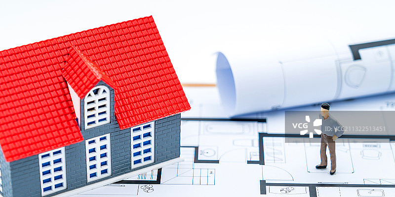 房子模型、人偶放在房屋户型图图纸上——买房装修概念图片素材