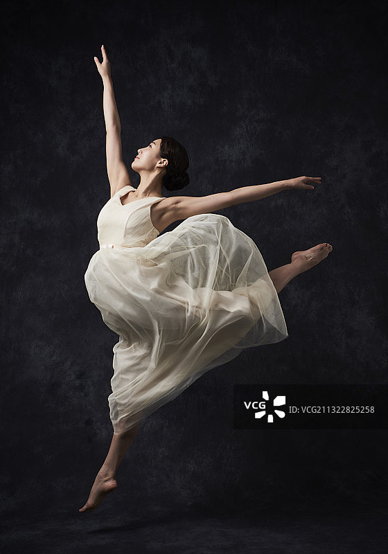 在黑色背景中跳芭蕾舞的白裙女人图片素材
