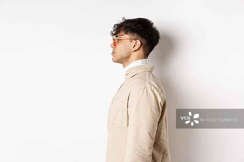 青年男子靠在白色背景墙上的侧面照图片素材