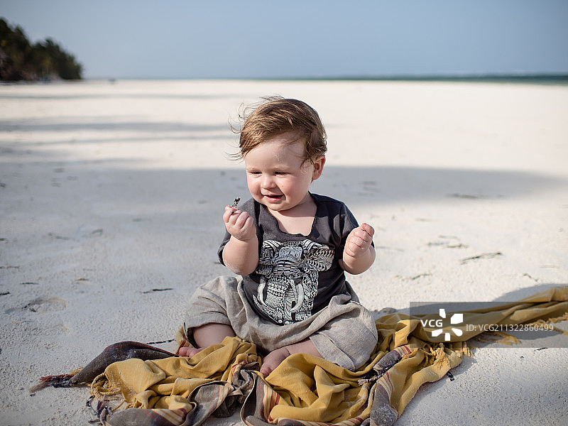 在坦桑尼亚桑给巴尔北部地区马特维海滩上坐在沙滩上的可爱女婴图片素材