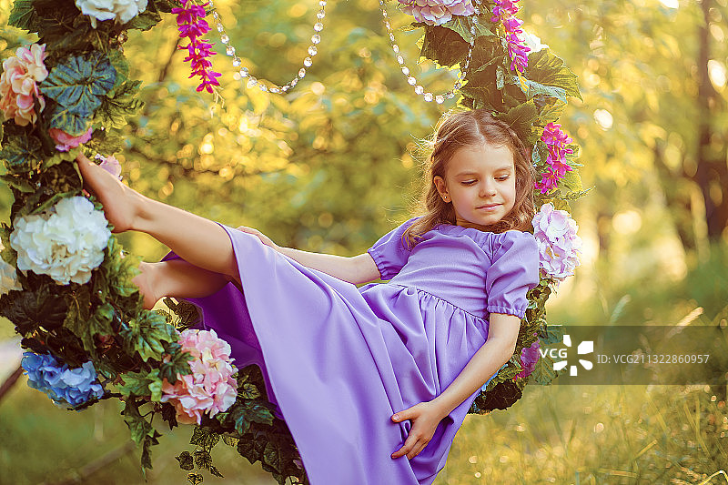 女孩坐在开花植物旁图片素材
