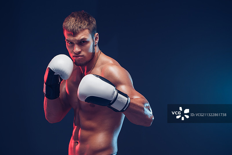 黑色背景下，戴着拳击手套的赤膊拳击手肖像图片素材