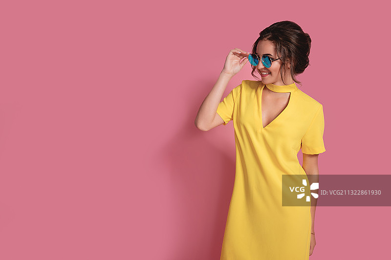 戴太阳镜的女人站在粉色背景前图片素材