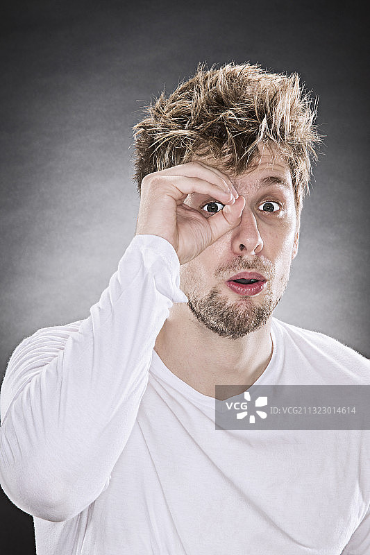 用手指在眼前画圈的年轻男子肖像图片素材