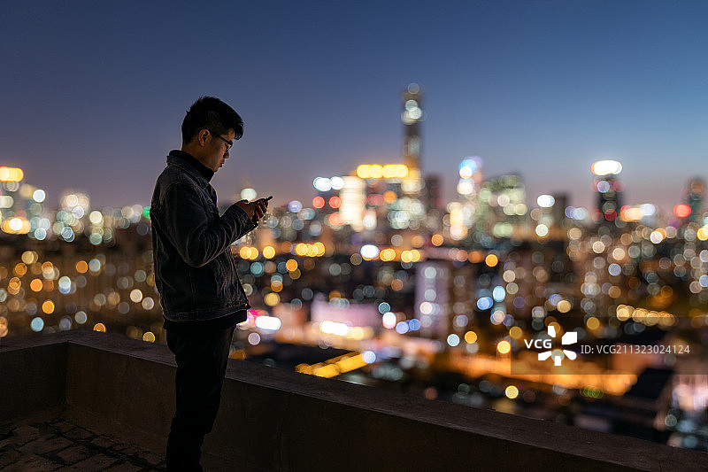 北京国贸CBD天际线夜景下看手机的人图片素材