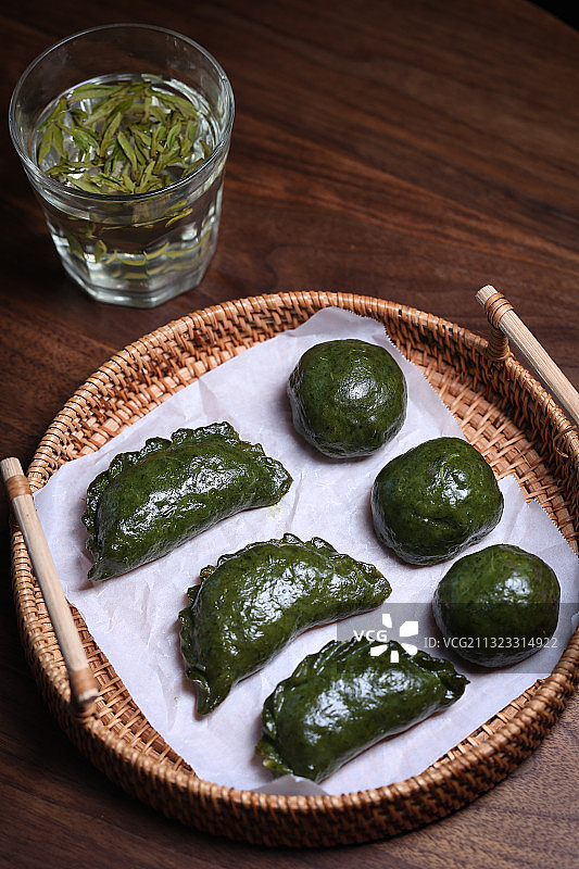 放在竹盘里的传统中式小吃清明果和龙井绿茶图片素材